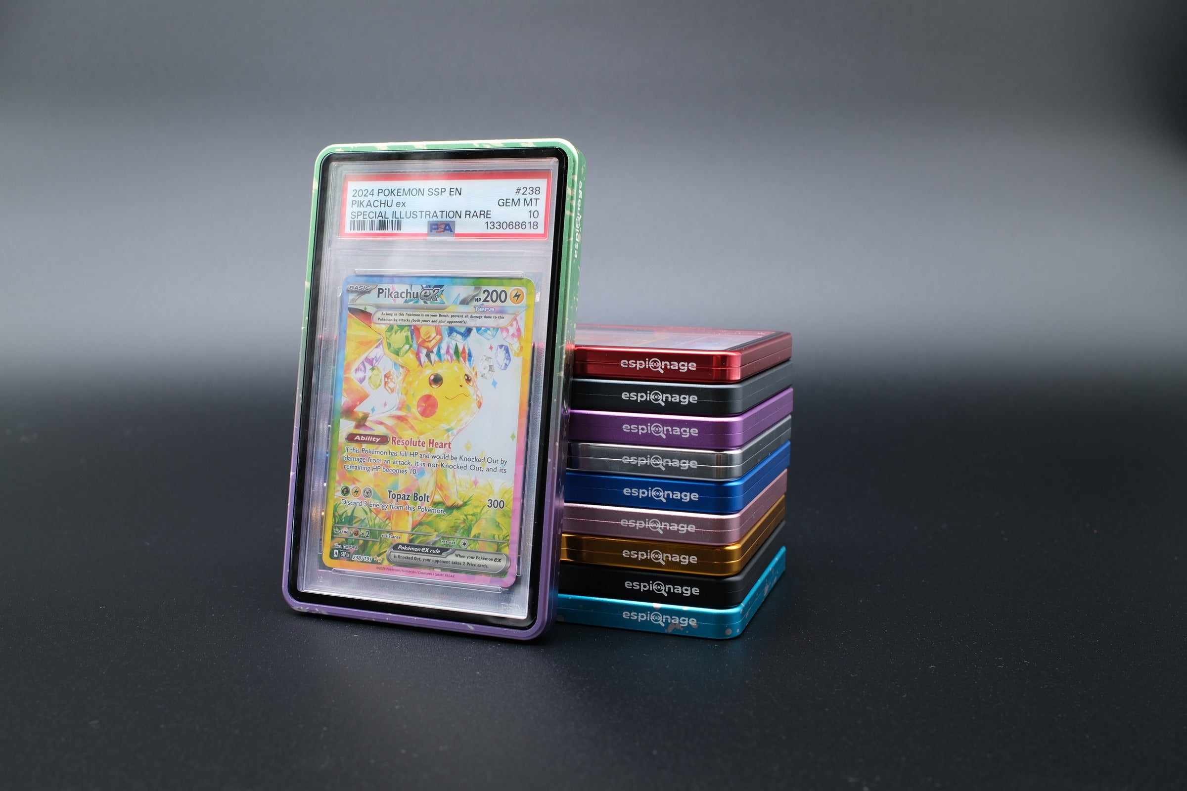 Green and Purple Speckle Aluminium Slab Guard holding a PSA graded Pokemon card